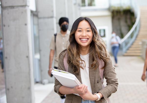 Smiling young woman carrying books