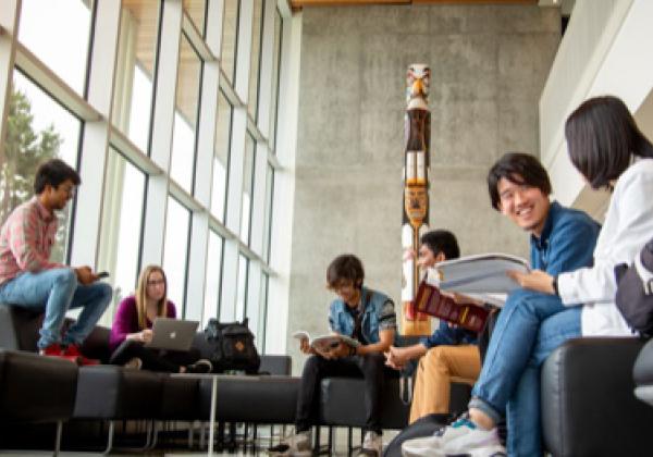 Students in a building. They are interacting in small groups. 